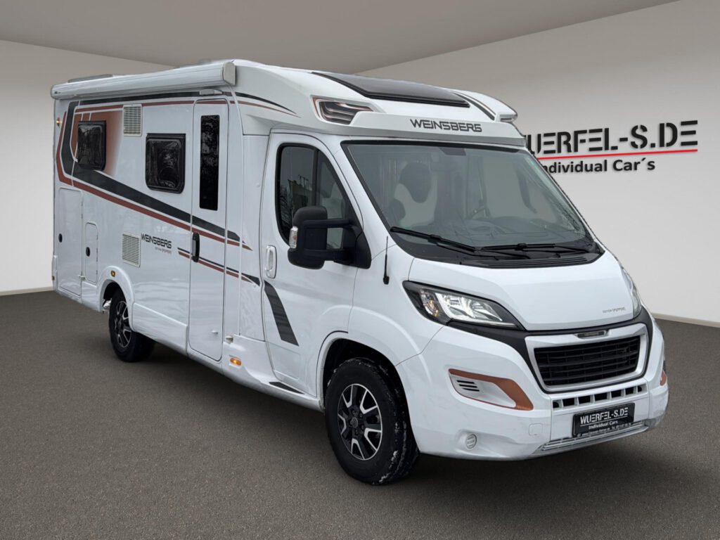 Weißes teilintegriertes Weinsberg Wohnmobil mit Markise, von schräg vorn aufgenommen.