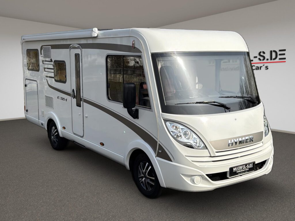 Helles vollintegriertes Hymer Exsis-i Wohnmobil mit dunklen Dekorstreifen und Markise, von schräg vorn.