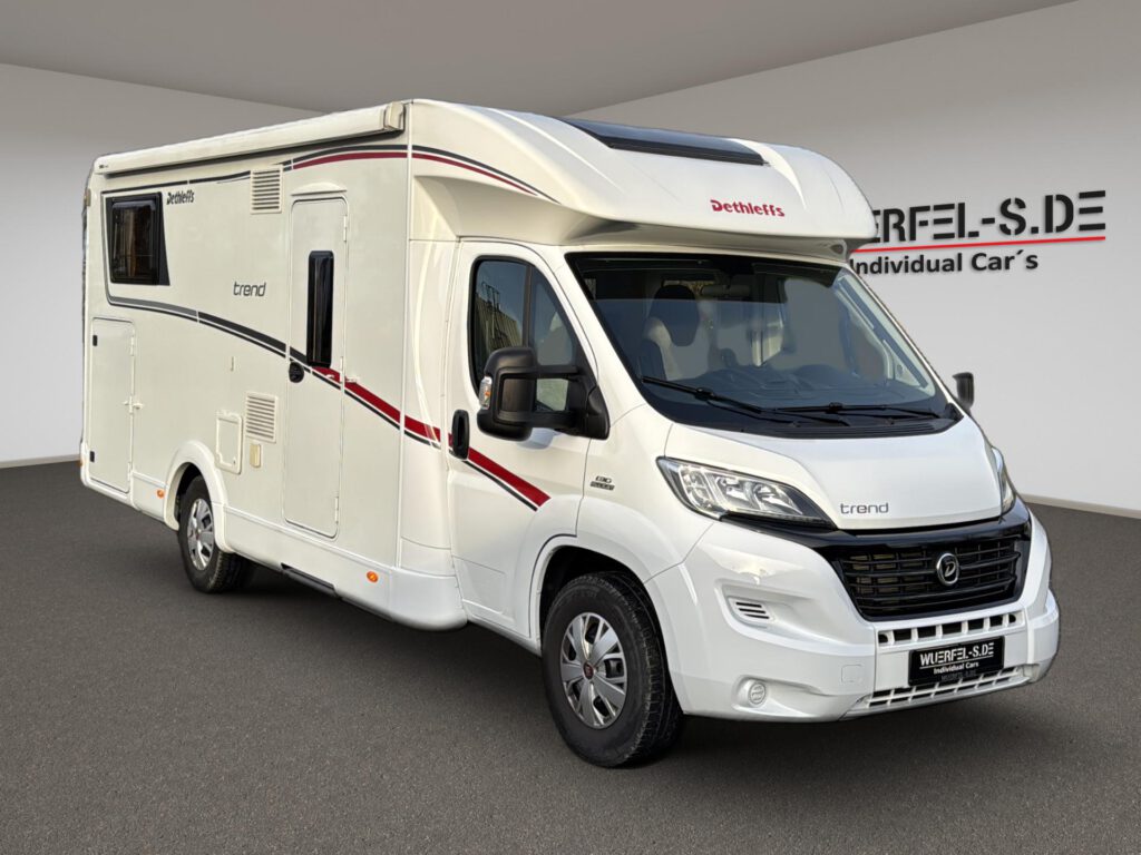 Weißes teilintegriertes Dethleffs Trend Wohnmobil mit roten und dunklen Dekorstreifen, von schräg vorn.