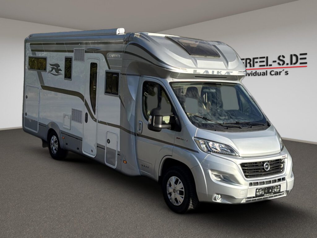 Silbernes teilintegriertes Laika Kreos Wohnmobil mit Markise und großem Dachfenster über dem Fahrerhaus, in Dreiviertelansicht.